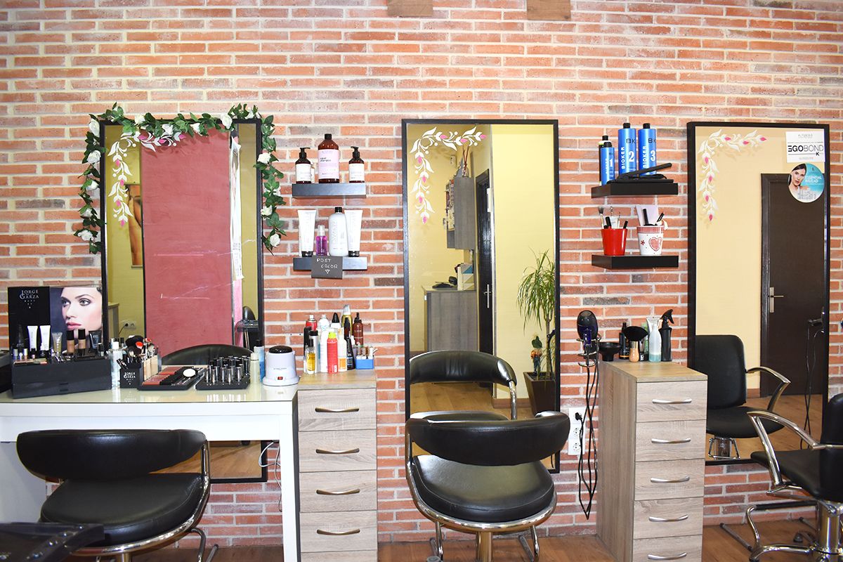 Foto frontal de los tres tocadores de la peluquería. Uno de ellos con los productos de maquillaje y los otros dos con los de peluquería.