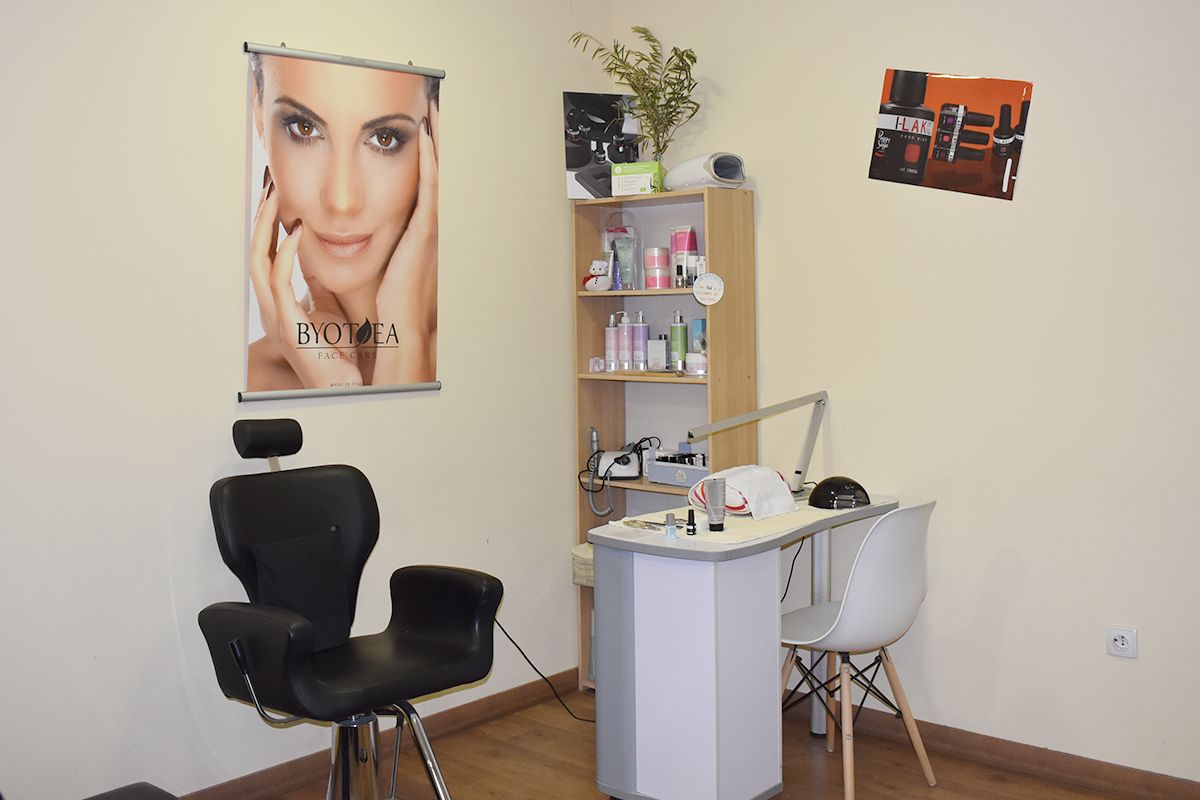 Zona de manicura donde hay una mesa con sillas y una estantería con productos.