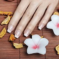 Manicura francesa con el fondo con dos velas en forma de flor y detalles de flor seca.