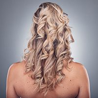Chica de espalda con el pelo rubio con mechas y ondas.